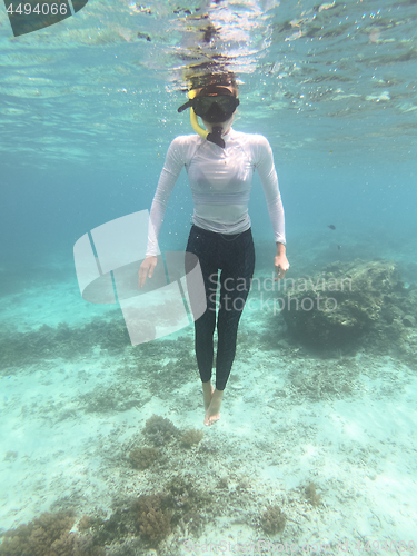 Image of Woman with mask snorkeling in blue sea.