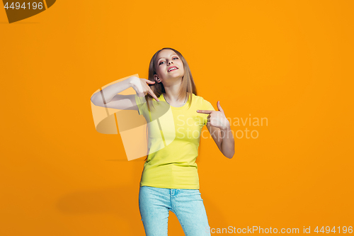 Image of The happy teen girl standing and smiling against orange background.