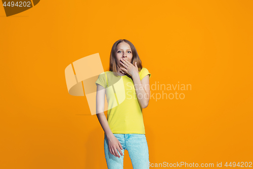 Image of Beautiful teen girl looking suprised isolated on orange