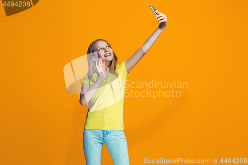 Image of The happy teen girl standing and smiling against orange background.