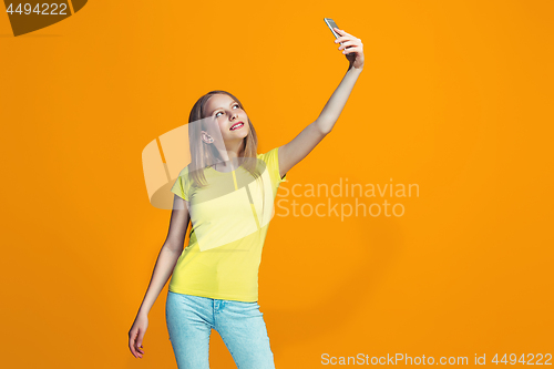 Image of The happy teen girl standing and smiling against orange background.