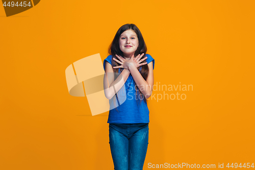 Image of The happy teen girl standing and smiling against orange background.