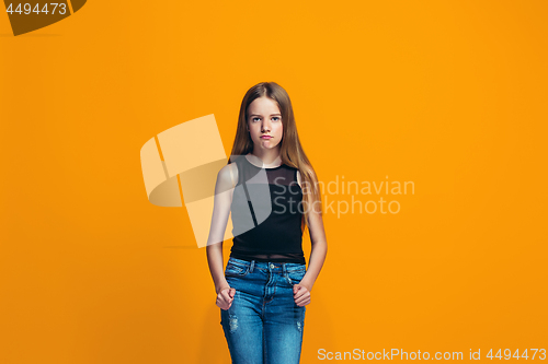 Image of Portrait of angry teen girl on a orange studio background