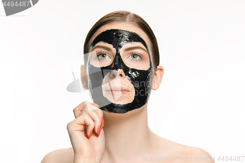 Image of Young beautiful woman applying a mask for the face of the therapeutic black mud. Spa treatment