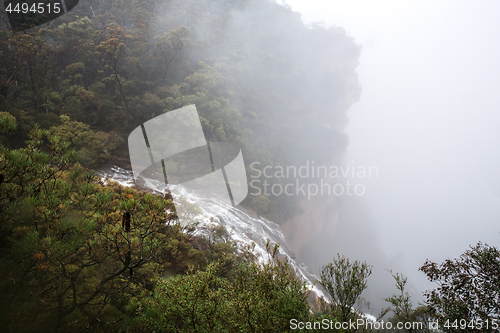 Image of Waterfall flows off the cliff into the foggy abyss