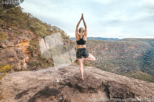 Image of Female strength yoga balance asana mountain cliff ledge