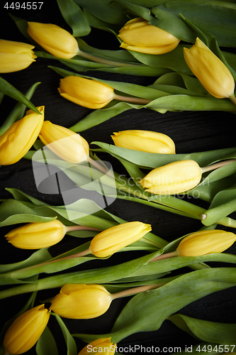 Image of Yellow tulips placed on black table. Top view with flat lay