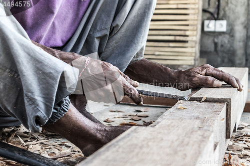 Image of Close up of warn hands of carpenter working in traditional manual carpentry shop in a third world country.