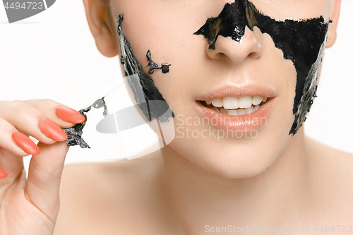 Image of Young beautiful woman applying a mask for the face of the therapeutic black mud. Spa treatment