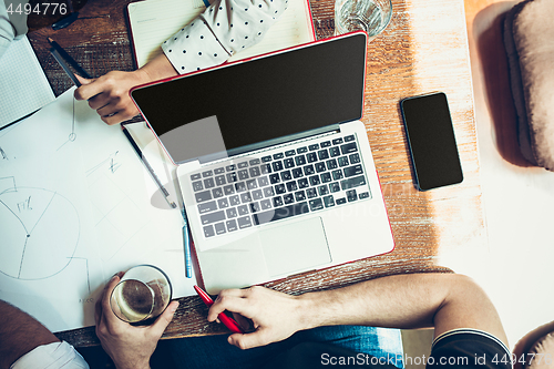 Image of The hands of people working and relaxing in pub.