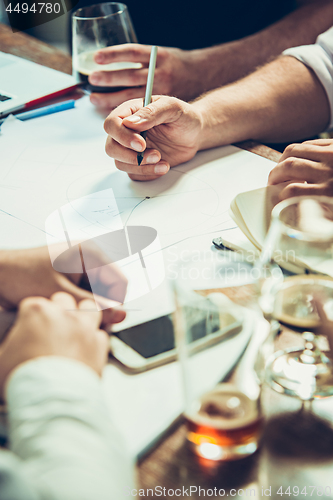 Image of The hands of people working and relaxing in pub.