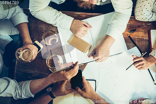 Image of The hands of people working and relaxing in pub.