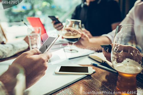 Image of The hands of people working and relaxing in pub.