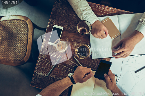 Image of The hands of people working and relaxing in pub.