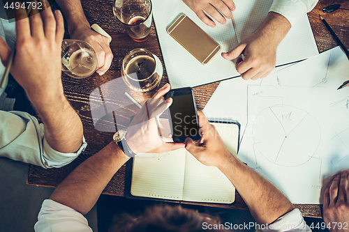 Image of The hands of people working and relaxing in pub.