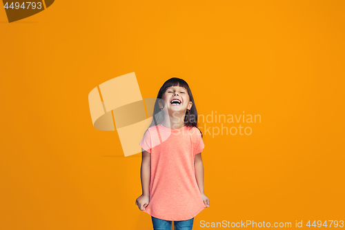 Image of The happy teen girl standing and smiling against orange background.