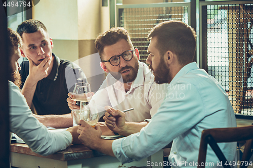 Image of Young cheerful people smile and gesture while relaxing in pub.