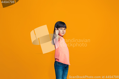 Image of The happy teen girl standing and smiling against orange background.