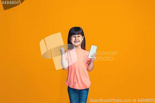 Image of The happy teen girl standing and smiling against orange background.