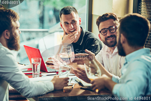 Image of Young cheerful people smile and gesture while relaxing in pub.