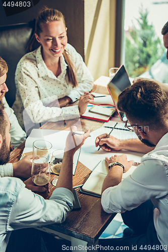 Image of Young cheerful people smile and gesture while relaxing in pub.