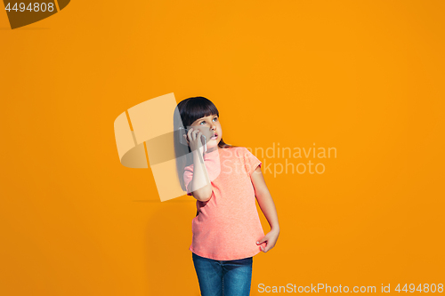 Image of The happy teen girl standing and smiling against orange background.