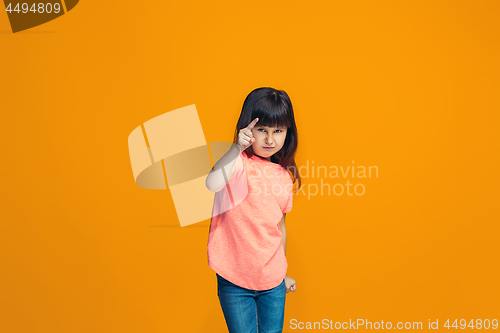 Image of The happy teen girl pointing to you, half length closeup portrait on orange background.