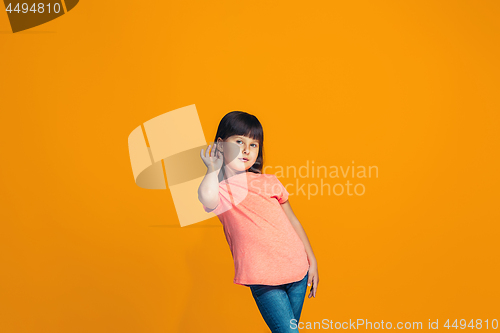 Image of The young teen girl whispering a secret behind her hand over orange background