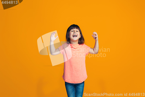 Image of The happy teen girl standing and smiling against orange background.