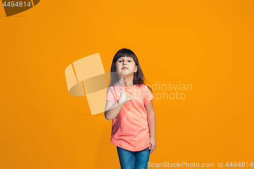 Image of The happy teen girl standing and smiling against orange background.