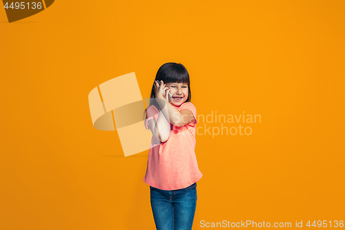 Image of The happy teen girl standing and smiling against orange background.