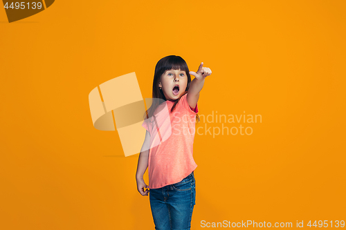 Image of Beautiful teen girl looking suprised isolated on orange