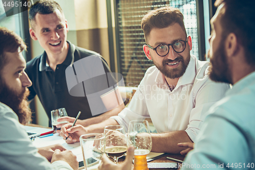 Image of Young cheerful people smile and gesture while relaxing in pub.