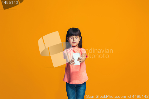 Image of The happy teen girl standing and smiling against orange background.