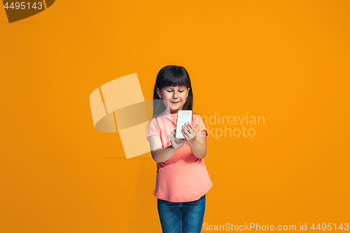 Image of The happy teen girl standing and smiling against orange background.