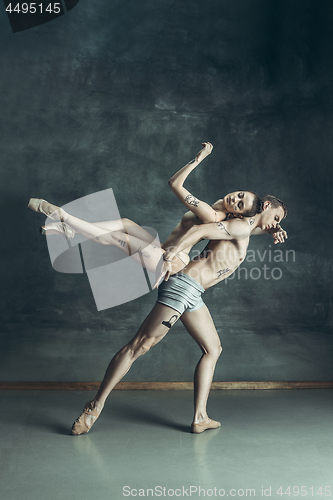 Image of The young modern ballet dancers posing on gray studio background