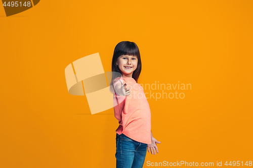 Image of The happy teen girl pointing to you, half length closeup portrait on orange background.