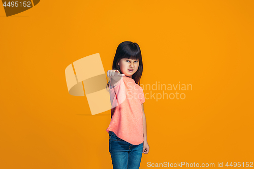 Image of The happy teen girl pointing to you, half length closeup portrait on orange background.