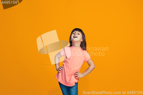 Image of The happy teen girl standing and smiling against orange background.