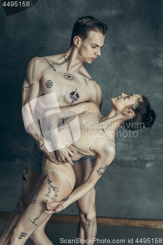 Image of The young modern ballet dancers posing on gray studio background