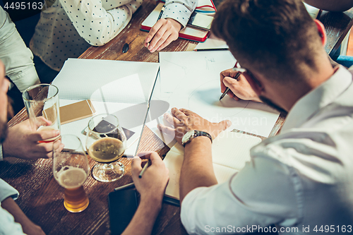 Image of Young cheerful people smile and gesture while relaxing in pub.