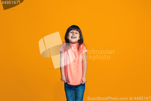 Image of The happy teen girl standing and smiling against orange background.