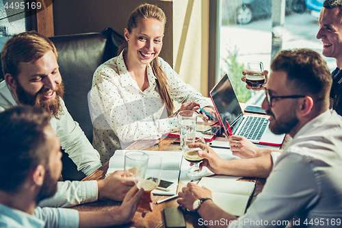 Image of Young cheerful people smile and gesture while relaxing in pub.