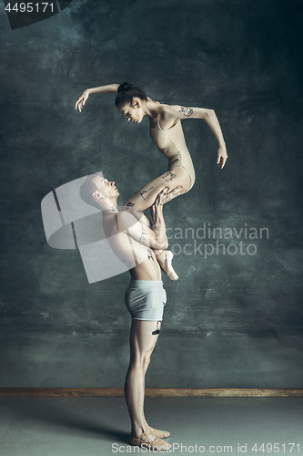 Image of The young modern ballet dancers posing on gray studio background