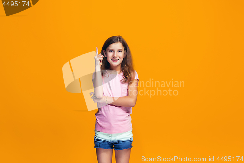 Image of Beautiful teen girl looking suprised isolated on orange