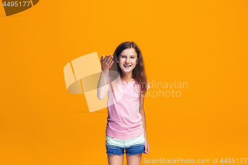 Image of Beautiful teen girl looking suprised isolated on orange