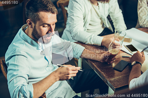 Image of Young cheerful people smile and gesture while relaxing in pub.