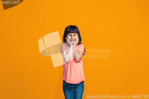 Image of The happy teen girl standing and smiling against orange background.