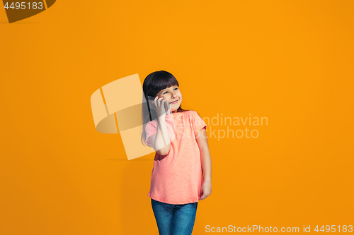 Image of The happy teen girl standing and smiling against orange background.