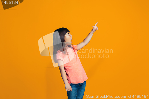 Image of Beautiful teen girl looking suprised isolated on orange